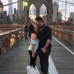 Reunited couple kissing on the Brooklyn Bridge at night in New York