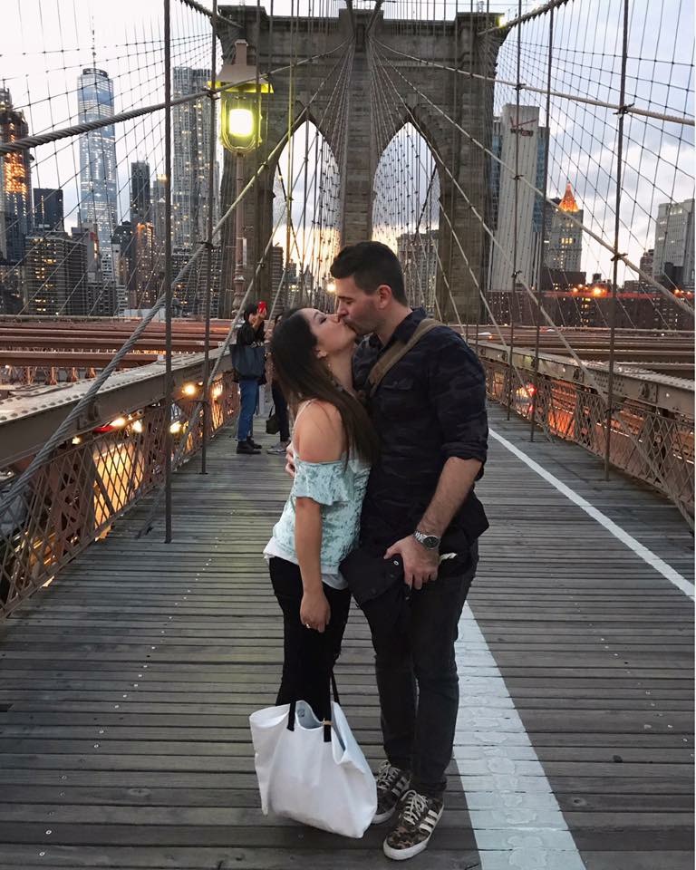 Reunited couple kissing on the Brooklyn Bridge at night in New York