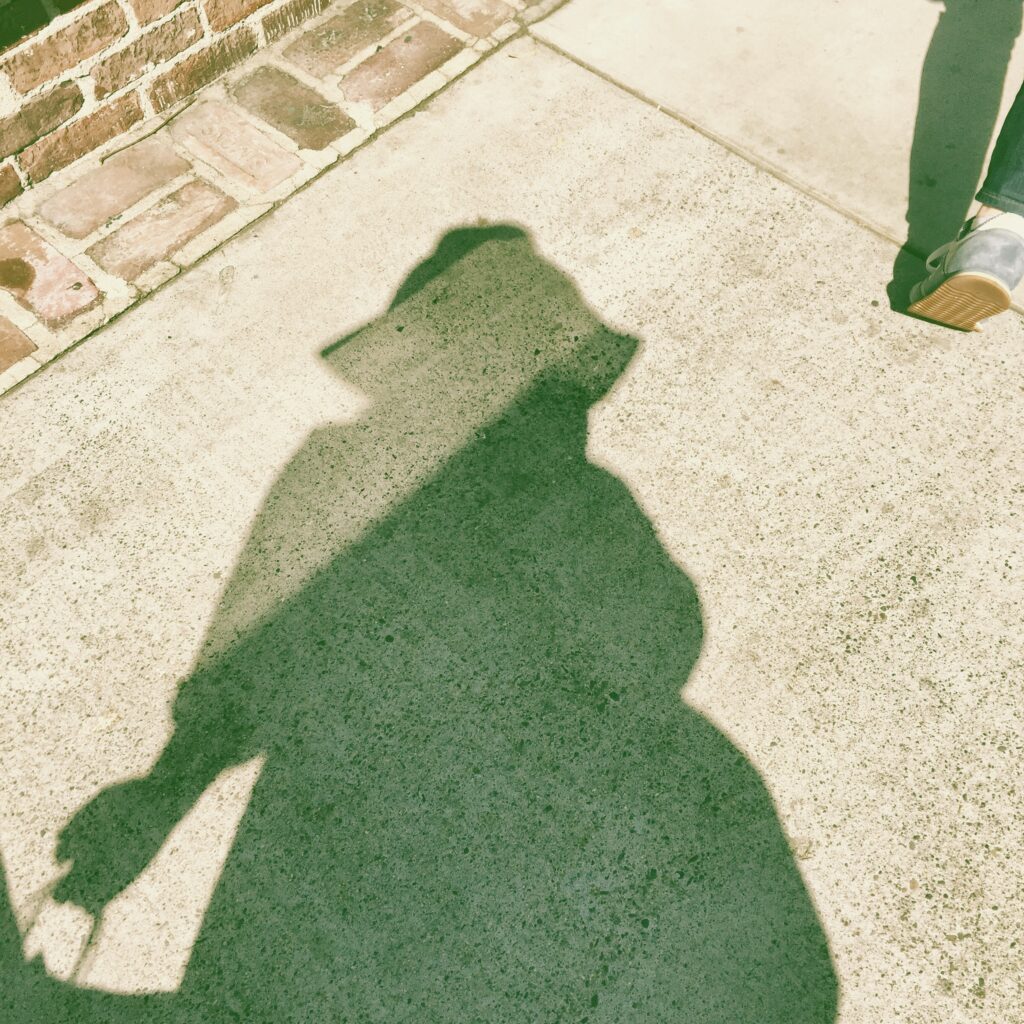Shadow in the sunlight wearing a floppy hat